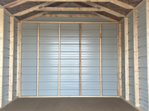 Interior of a small shed with exposed wooden framing, metal panel walls, and oriented strand board (OSB) on the roof